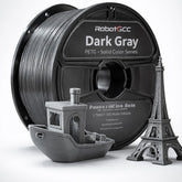 Spool of RobotGCC gray 3D printing filament with printed models on a white background