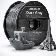 Spool of RobotGCC gray 3D printing filament with printed models on a white background