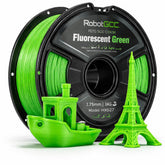 Spool of RobotGCC Fluorescent Green 3D printing filament with 3D prints of a boat and Eiffel Tower.