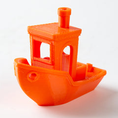 Orange 3D-printed toy boat with a detailed cabin on a white background