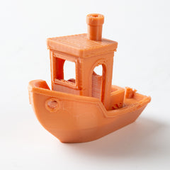 Orange 3D-printed toy boat on a white background