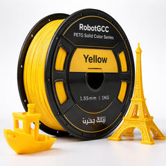 Spool of yellow 3D printing filament with small models of the Eiffel Tower and a boat on a white background.