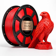 Red 3D printing filament spool next to a red falcon sculpture on a white background