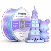 Spool of RobotGCC PLA filament and a 3D printed tower and bear figure in Bubble Purple color.
