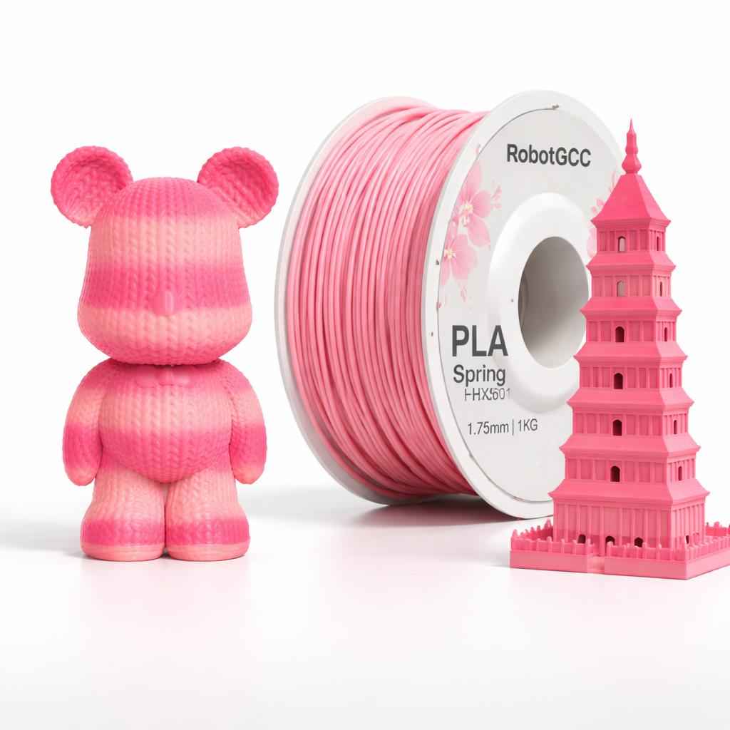 Pink 3D printed object, spool of pink filament, and pink model of a tower on a white background