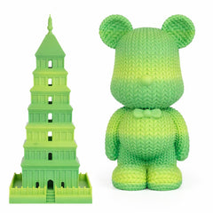 Green toy resembling the Leaning Tower of Pisa next to a green teddy bear on a white background