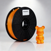 Spool of orange 3D printing filament and a small orange 3D printed bear figure on a gray background