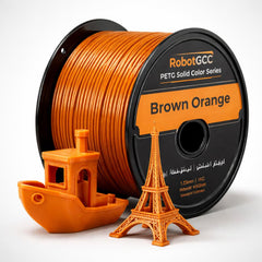 Spool of Brown Orange 3D printing filament with small models of a boat and Eiffel Tower.