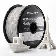 Spool of RobotGCC PETG filament with 3D prints of a boat and Eiffel Tower on a white background