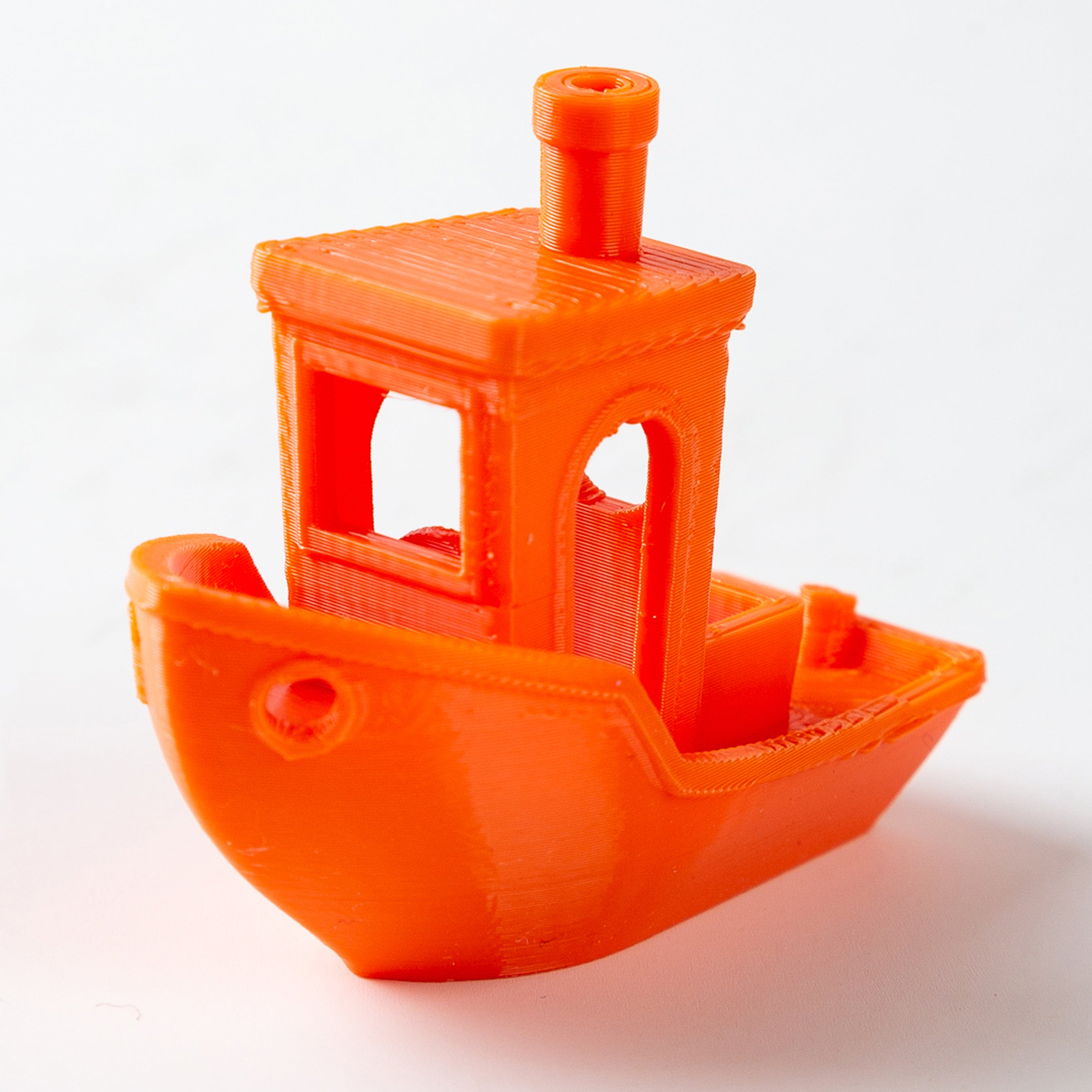 Orange 3D-printed toy boat with a detailed cabin on a white background