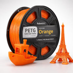 Spool of orange 3D printing filament with small models made from it on a white background