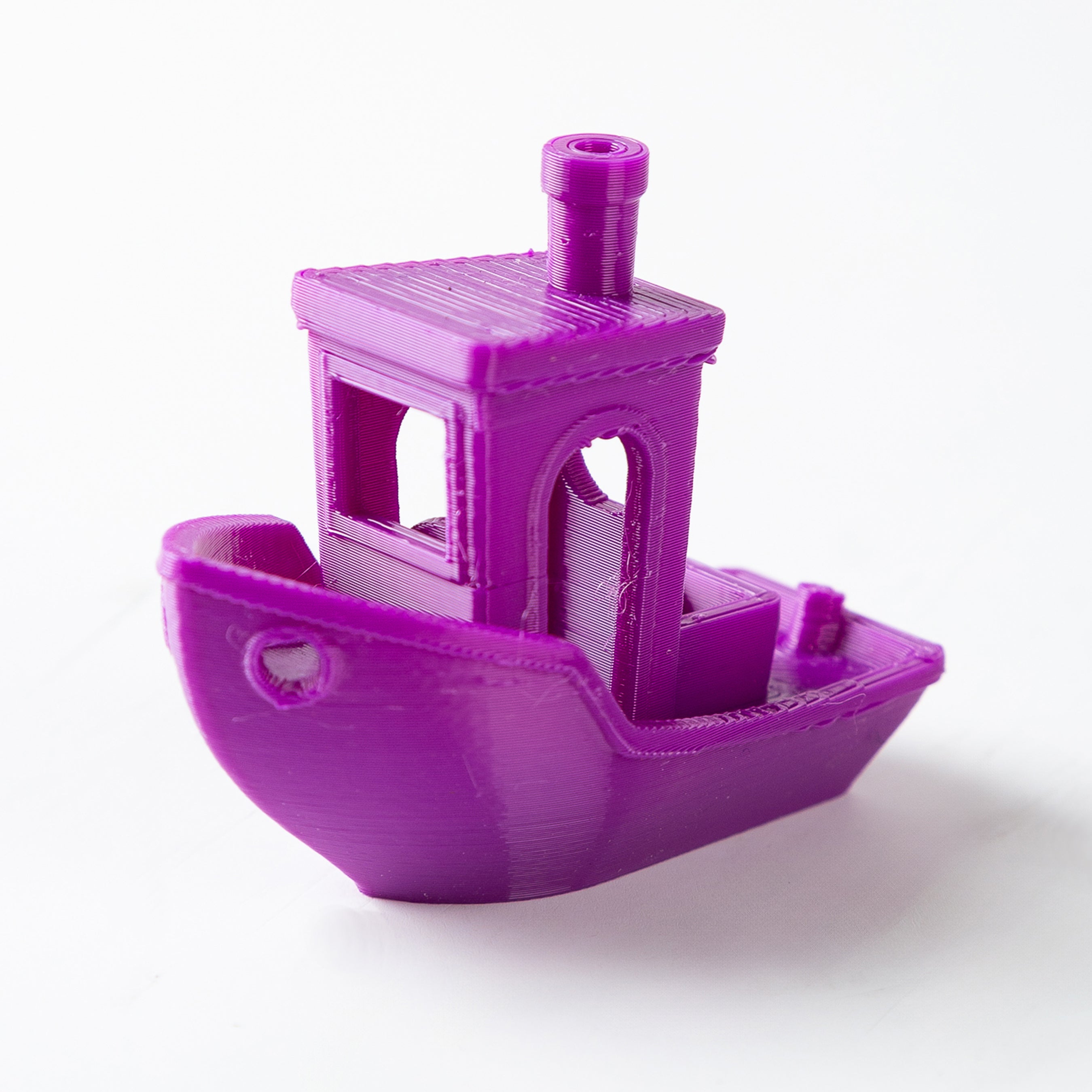 Purple 3D-printed toy boat on a white background