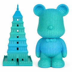 Turquoise toy bear and tower of Babel model on a white background