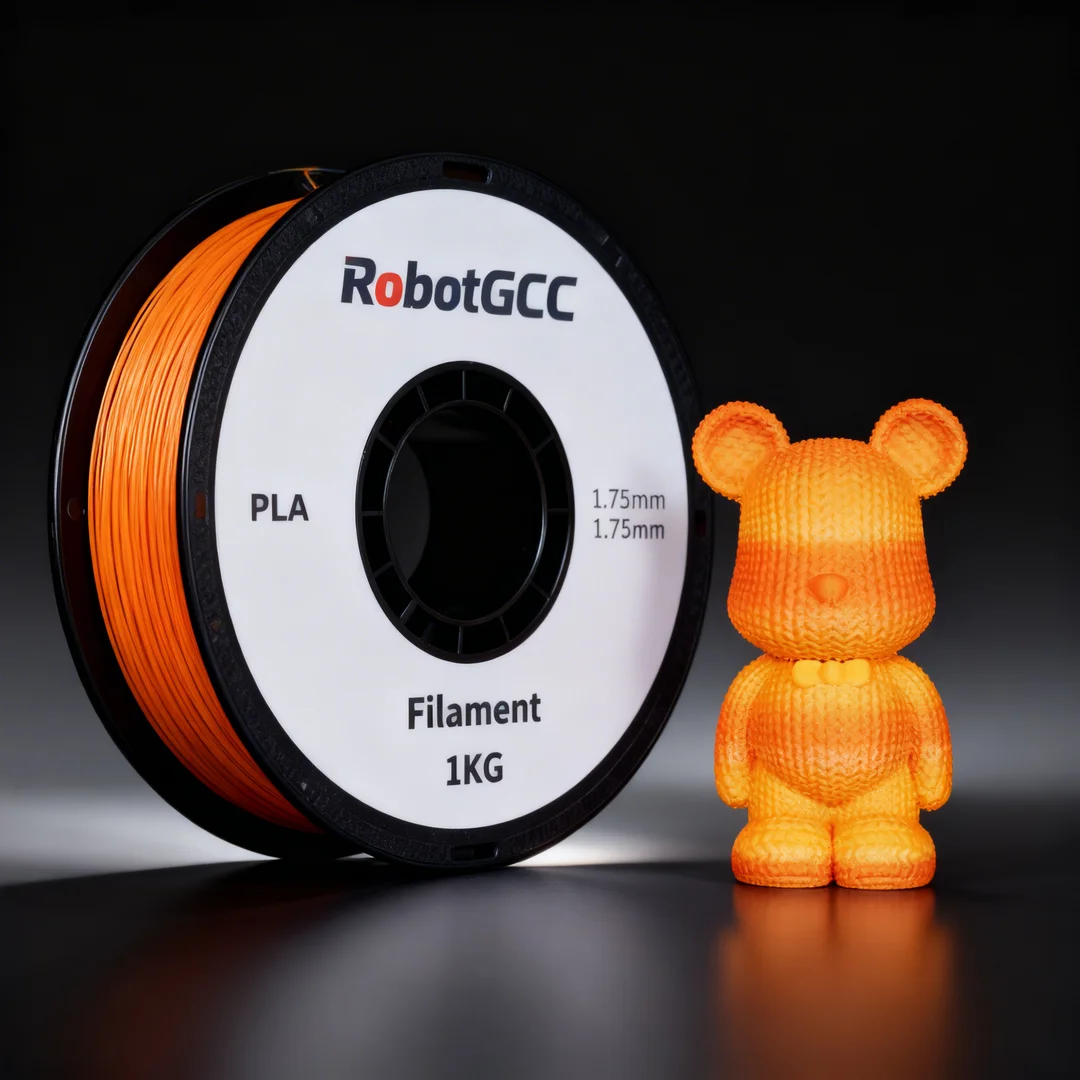 Spool of RobotGCC PLA filament and a small orange 3D-printed bear figure on a reflective surface with a dark background.